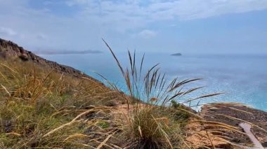 Çimenli bir yamaçta dolambaçlı toprak bir yol boyunca huzurlu bir yolculuk yaşayın. Sahnede kayalık çıkıntılar, okyanus manzarası ve ıssız bir tekne yer alıyor.