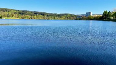 Bu büyüleyici video, dingin gölü, gür ağaçları ve görkemli dağlarıyla nefes kesici bir manzara sergiliyor. İzleyicileri doğaya dalmaya davet ediyor.