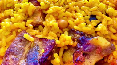 Lezzetli bir kasede taze tavuk ve nohut ile kaplanmış renkli sarı pirinç tabağı.