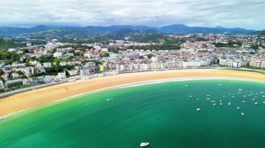 İşte canlı bir sahil manzarası, berrak turkuaz sular ve pitoresk bir sahil kenti içeriyor.