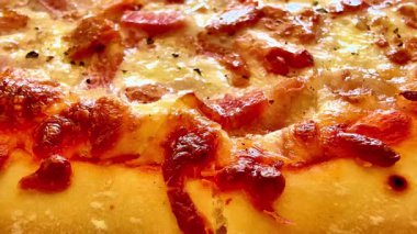 Ağız sulandırıcı ve cezbedici bir yakın çekim. Üstünde erimiş peynir ve pepperoni katmanları olan yeni pişmiş bir pizza.