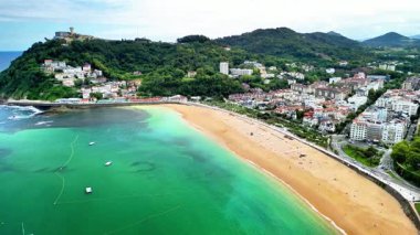 Göz kamaştırıcı hava görüntüleri canlı bir plajı, kristal turkuaz suları ve büyüleyici bir sahil kasabasını güzel bir şekilde gösteriyor.