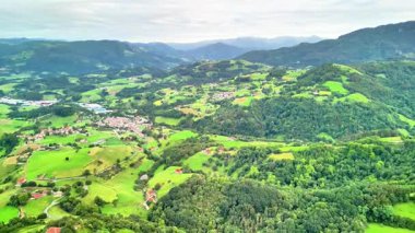 Canlı yeşil tarlaların ve dinamik, bulutlu gökyüzünün altındaki yemyeşil ormanların havadan görünüşünün tadını çıkarın.