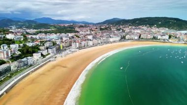 Nefes kesici bir sahil ve kristal berrak suların yer aldığı canlı bir kıyı şehrini gösteren çarpıcı bir hava manzarası.