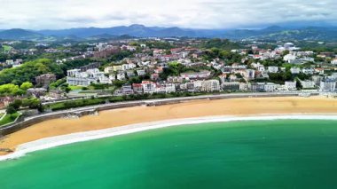 Muhteşem bir hava manzarası sahilin kenarında, yemyeşil tepelerle çevrili güzel bir kıyı şehrini gösteriyor.