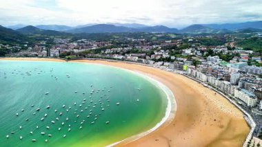 Hava manzarası güzel bir şekilde sergileniyor. Parlak bir şehir ve uzaktaki görkemli dağlar tarafından çerçevelenmiş çarpıcı bir sahil.
