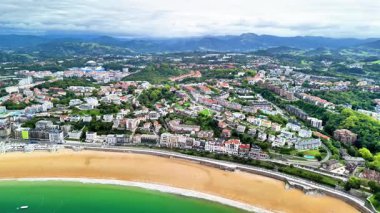 Hava manzarası, etrafını çevreleyen güzel plajları ve resimli tepeleri olan canlı bir kıyı şehrini gösteriyor.