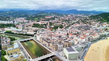 Nefes kesen bir hava görüntüsü, bereketli dağların kucakladığı dolambaçlı bir nehrin yanında yer alan canlı bir şehri gösteriyor.