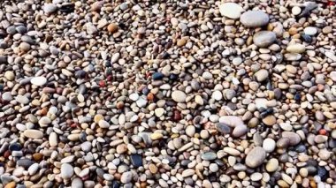 Etrafını saran rahatlatıcı dalgalar ve canlı taş dokuları olan güzel bir çakıl taşı kumsalı keşfedip keşfedin.