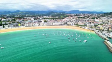 Turkuaz sular ve yelkenli teknelerle çevrili güzel bir sahil kasabasının çarpıcı hava manzarasının tadını çıkarın.