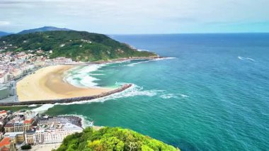 Kumlu plajı ve pırıl pırıl zümrüt suları olan çarpıcı bir sahil şehrinin canlı hava manzarasının tadını çıkarın.