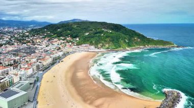 Bir hava görüntüsü çarpıcı bir sahili, çarpan dalgaları, işlek bir şehri ve güzel yemyeşil tepeleri gözler önüne serer.