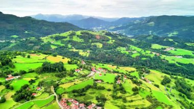 Yeşil tepelerin ve vadilerin, arka planda tuhaf köylerin ve dağların çarpıcı hava görüntüleri..