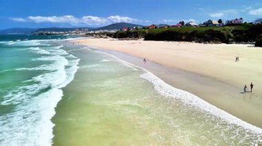 Şaşırtıcı derecede güzel bir plaj sahnesi yumuşak altın kum, yuvarlanan yumuşak dalgalar ve berrak mavi gökyüzü