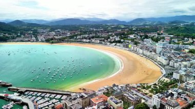 Renkli tekneler ve çarpıcı manzaralarla bezenmiş canlı bir sahili güzel bir şekilde yansıtan nefes kesici bir hava manzarası.