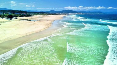 Huzurlu bir sahil sahnesi kristal berraklığında turkuaz su, yumuşak kumlu kıyılar ve davetkar canlı bir manzara.