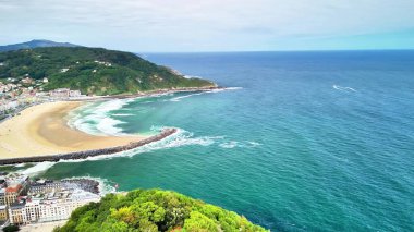 Kumlu plajı ve pırıl pırıl zümrüt suları olan çarpıcı bir sahil şehrinin canlı hava manzarasının tadını çıkarın.