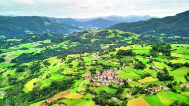Parlak yeşil tepelere kurulmuş güzel bir köyü gösteren nefes kesici bir hava manzarası yaşayın.