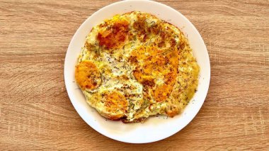 Beyaz bir tabakta servis edilen yumuşak bir omlet, kahvaltı için ideal ya da enfes bir brunch toplantısı için.