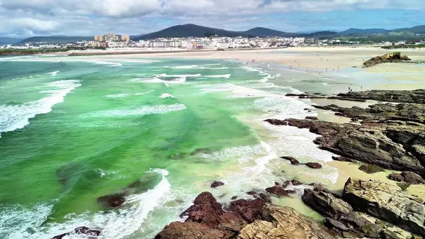 Parlak yeşil denizleri, yumuşak dalgaları ve kumlu plajları olan nefes kesici bir kıyı manzarası.