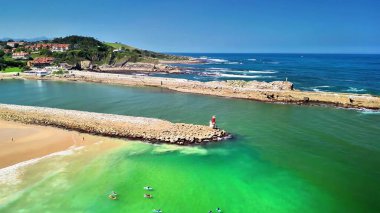 Sersemletici yeşil suları ve kayalık oluşumlarıyla berrak bir sahilin nefes kesici manzarası.