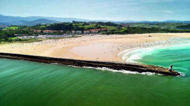 Nefes kesici bir hava manzarası, berrak mavi gökyüzünün altında bir iskeleyi gösteren çarpıcı bir sahil manzarası.