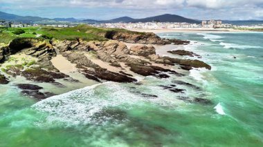 A breathtaking glimpse of a coastal landscape with waves crashing on rocks, showcasing natural beauty.
