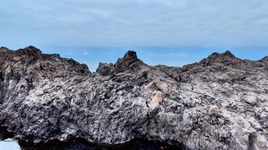 Sersemletici sahil kaya oluşumları ve bulutlu bir gökyüzünün altında sakin sular. Barış isteyen doğa aşıkları için ideal.