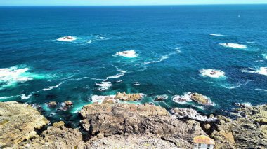 Engebeli bir kıyı şeridinin çarpan dalgaları ve berrak mavi suların çarpıcı görüntülerini...