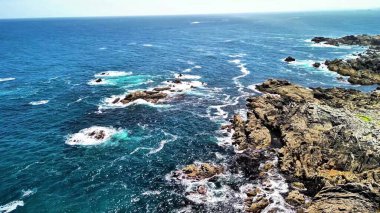 Hava manzarası dalgaları güzel yakalar engebeli kıyılara çarpan canlı mavi gökyüzü altında