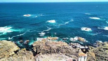 Engebeli bir kıyı şeridinin çarpan dalgaları ve berrak mavi suların çarpıcı görüntülerini...