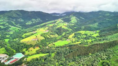 Sersemletici hava manzaraları canlı yeşil tepelerin ve bulutlu gökyüzünün altındaki yemyeşil vadilerin nefes kesici manzaralarını sergiliyor.