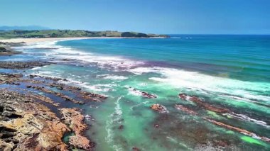 Kayalık uçurumlar ve turkuaz okyanus dalgalarının yer aldığı canlı bir plajın nefes kesici ve çarpıcı manzarasının tadını çıkarın.