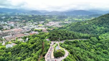 Sersemletici hava görüntüleri, dingin suların yanında yemyeşil bir yeşilliğe sahip canlı bir kıyı şehrini sergiliyor.