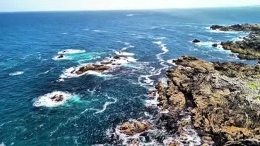 Hava manzarası dalgaları güzel yakalar engebeli kıyılara çarpan canlı mavi gökyüzü altında