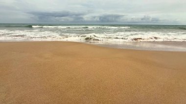 Yumuşak dalgalar ve yumuşak kumlar sergilenen güzel sakin bir sahil sahnesi, çeşitli rahatlama temaları için ideal.