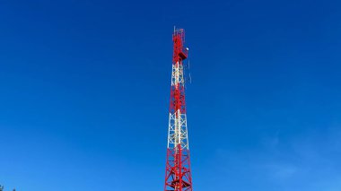 Parlak mavi gökyüzüne karşı modern iletişim teknolojisini temsil eden uzun ve sağlam bir telekom kulesi.