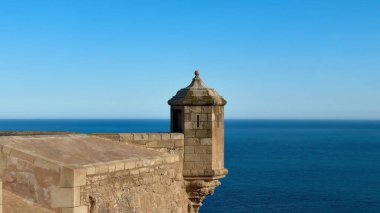 Uçsuz bucaksız okyanusu görkemli bir şekilde gören tarihi bir kale kulesini gösteren nefes kesici bir kıyı manzarası.