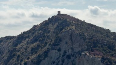 Issız bir kuleyi gösteren nefes kesici bir manzara heybetli bir şekilde dik bir tepenin tepesine tünemiş canlı bir gökyüzüne karşı.