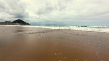 Sakin ve sakin bir sahil. Yumuşak, yumuşak dalgalar ve bulutlu bir gökyüzü. Rahatlamak ve huzurlu bir kaçış için mükemmel.