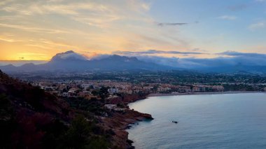 Gün batımında görkemli dağlar ve sakin suların çerçevelediği kıyı şehrinin nefes kesici manzarası manzarayı güzelleştiriyor.