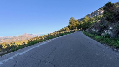 Güzel, dolambaçlı bir yol, zarif bir şekilde çevreleyen canlı yemyeşil ve şafak vakti nefes kesen dağlar.