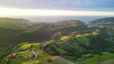 Gün batımında engin okyanus kıyısındaki yuvarlanan tepeleri gösteren nefes kesici bir hava manzarasının tadını çıkarın.