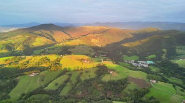 Soluk kesici hava manzarası yuvarlanan tepeler ve yumuşak güneş ışığı altında canlı yeşil alanlar..