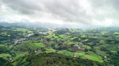 Bulutlu bir gökyüzünün altındaki yemyeşil tepelerin çarpıcı hava manzarası, dingin manzaralar ve geniş kırsal alanlar.