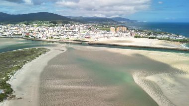 Hava görüntülerinde güzel bir şekilde huzurlu bir sahil kenti ve berrak, davetkar suların yer aldığı büyüleyici bir sahil kasabası görülüyor.