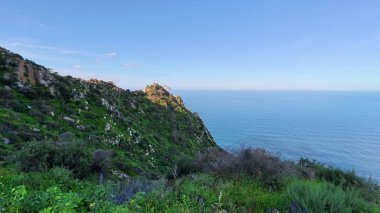 Parlak yeşillik ve berrak bir gökyüzünün altındaki dingin mavi okyanusla nefes kesici kıyı manzarasını deneyin.