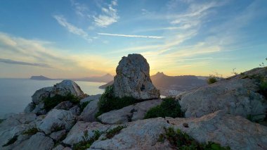 Çarpıcı manzarada nefes kesici bir kayalık kıyı şeridi, canlı bir gün batımı ve büyüleyici sakin bir okyanus manzarası var.