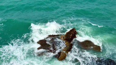 Titreşimli okyanus dalgaları resim gibi kaya oluşumları etrafında dönerek güçlü güzellikler sergiliyor.