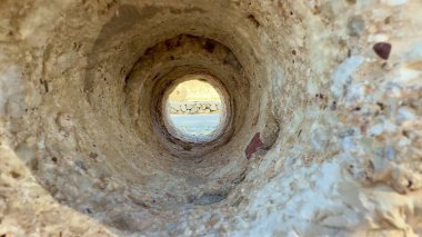 Dairesel bir kaya tüneli tarafından çerçevelenmiş büyüleyici ve nefes kesici bir manzara var, nefes kesici doğal bir manzara sergiliyor.